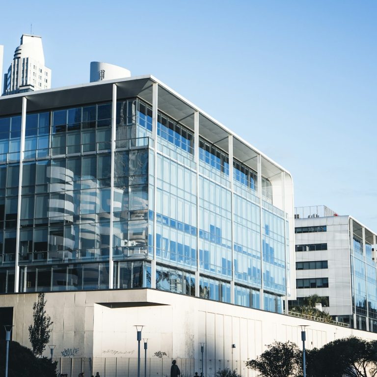 Moderne Bürogebäude mit großen Glasfenstern und klarer Struktur im Tageslicht.