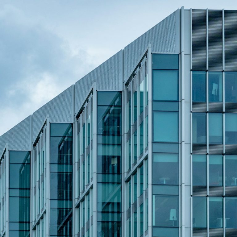 Moderne Bürogebäude mit gläserner Fassade und schrägem Dach.